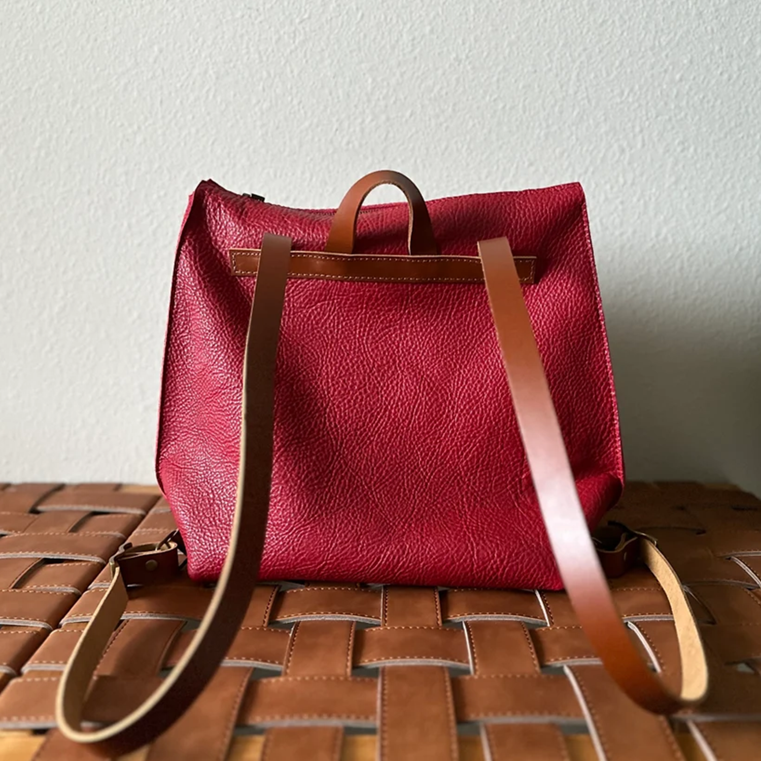 Scarlet Red Pebbled Trapezoid Rucksack With Tan Contrast Straps, Top Rear Hand Loop, Exterior Zip Slip Pocket And Multi-Slot Interior Dividers Backpack