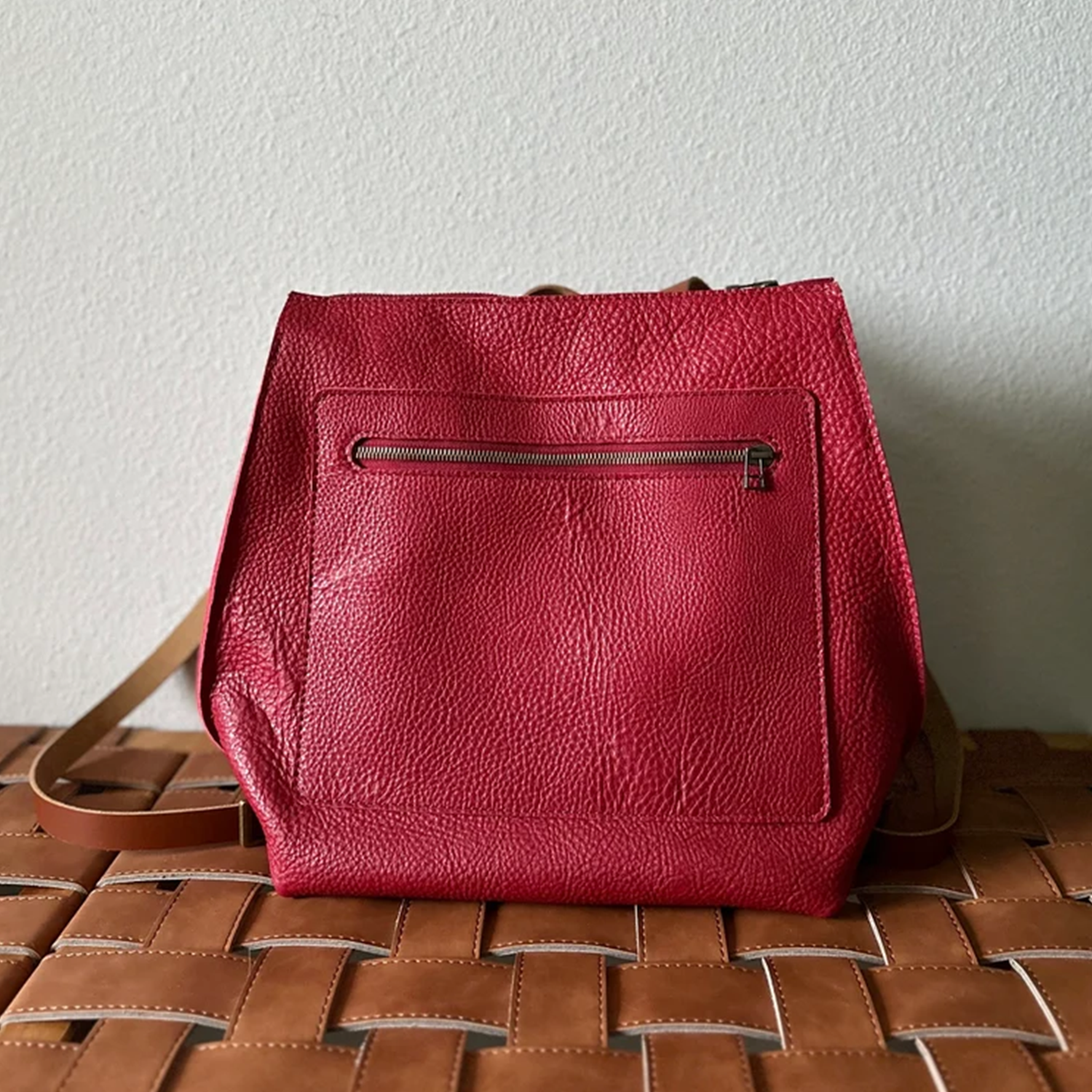 Scarlet Red Pebbled Trapezoid Rucksack With Tan Contrast Straps, Top Rear Hand Loop, Exterior Zip Slip Pocket And Multi-Slot Interior Dividers Backpack
